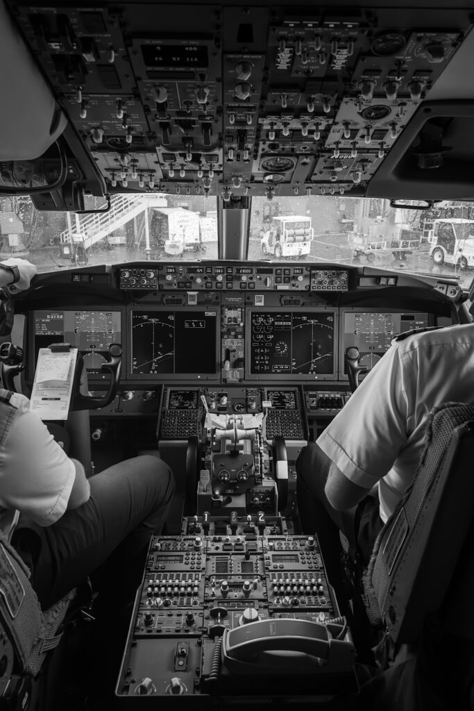 Detailed view of an airplane cockpit with two pilots in black and white.