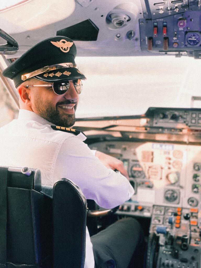 Smiling pilot in uniform in cockpit, exuding confidence and professionalism.